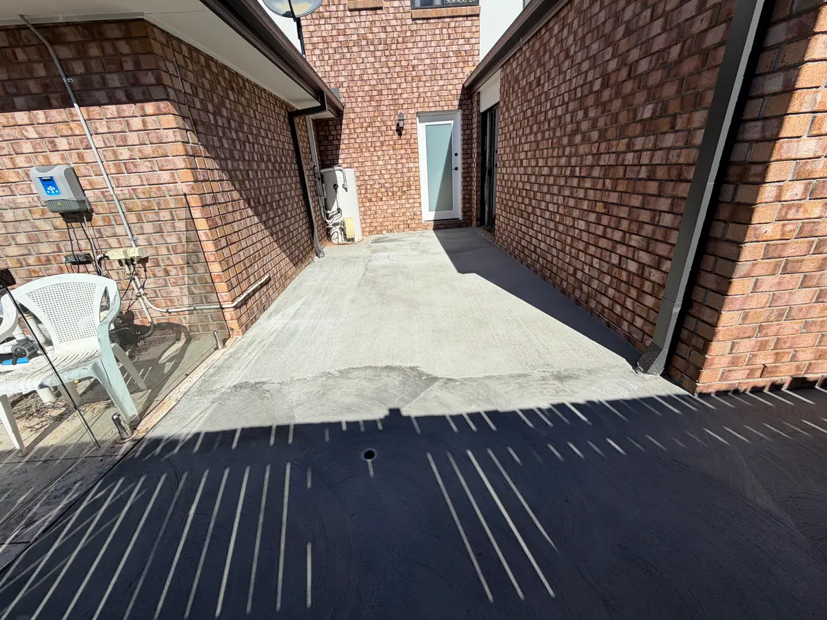 Courtyard slab poured between two brick walls at the back of a house
