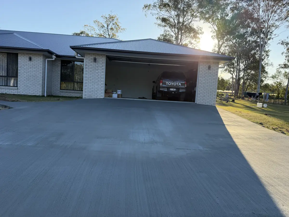 Finished concrete driveway running up to a double garage