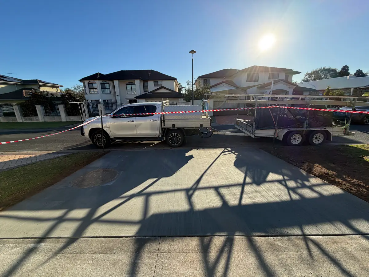 Driveway poured and taped off, with the work ute and trailer parked on the street