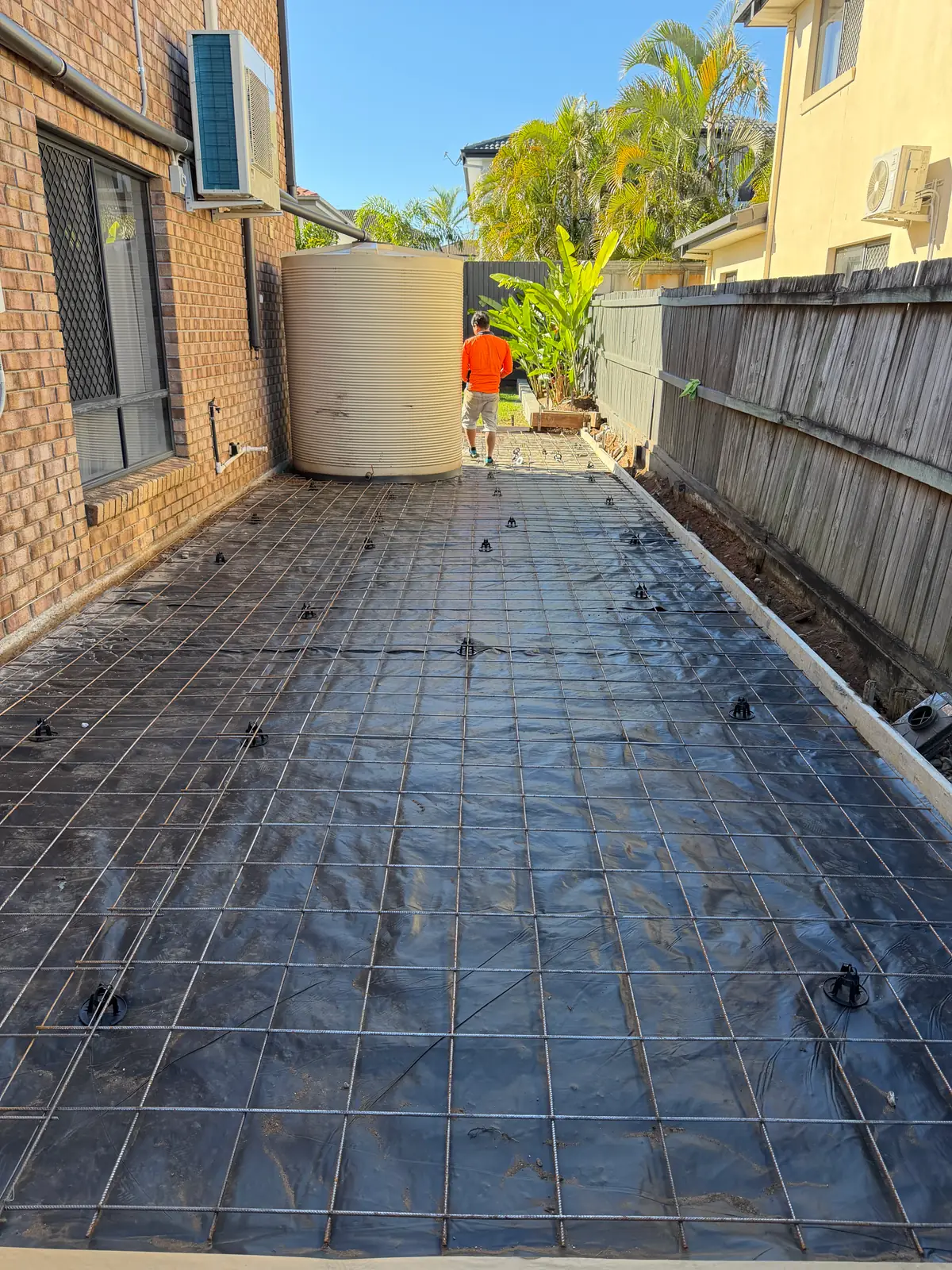 Side path formed up with membrane and steel mesh laid, worker in hi vis at the far end