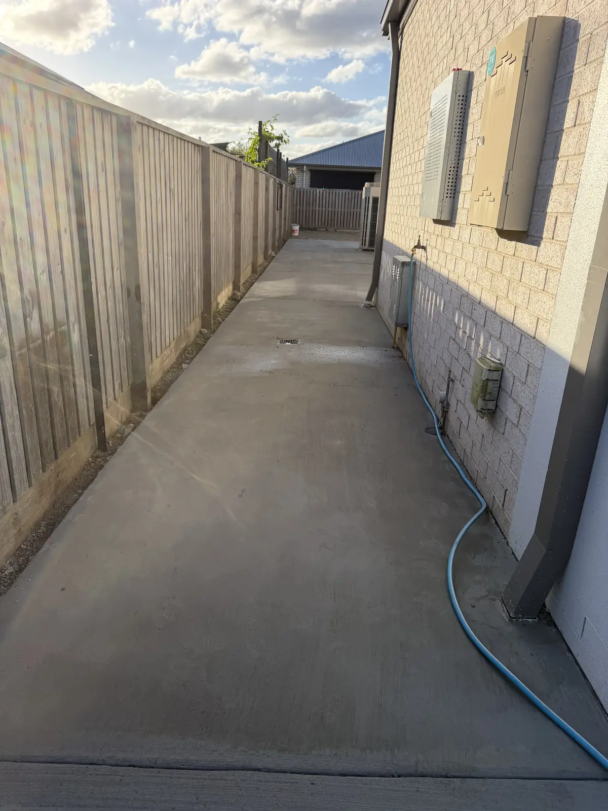 Narrow side path poured between a house and the fence